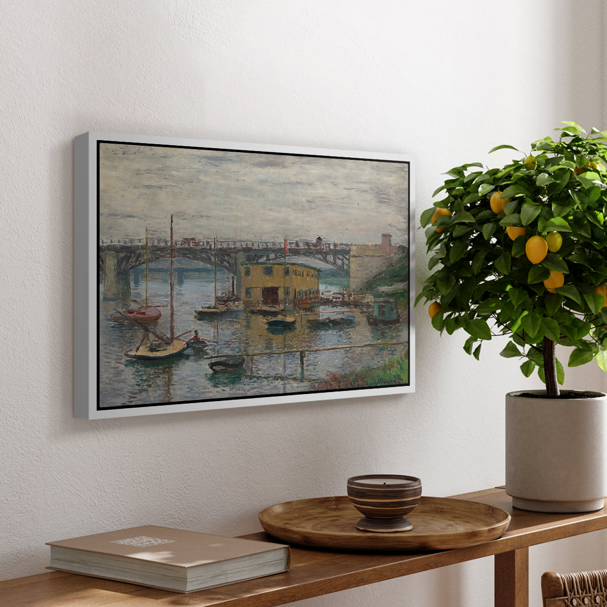 Bridge at Argenteuil on a Gray Day, c. 1876 by Claude Monet, presented in a white floater framed canvas featuring a bridge crossing river under gray sky with muted reflections, displayed above a hallway console table.