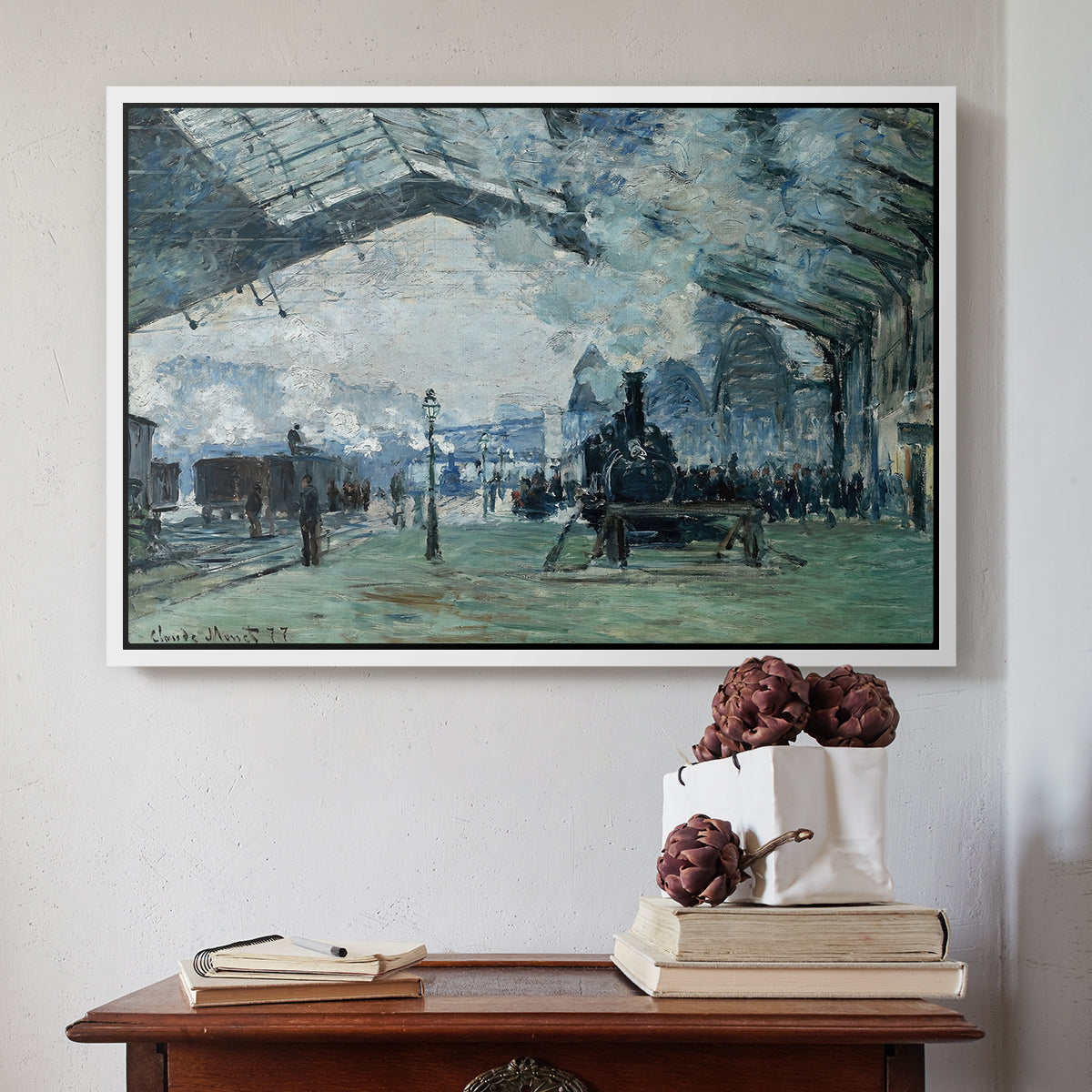 White floater framed canvas featuring The Saint-Lazare Station, 1877 by Claude Monet above an entryway table in a minimalist foyer.