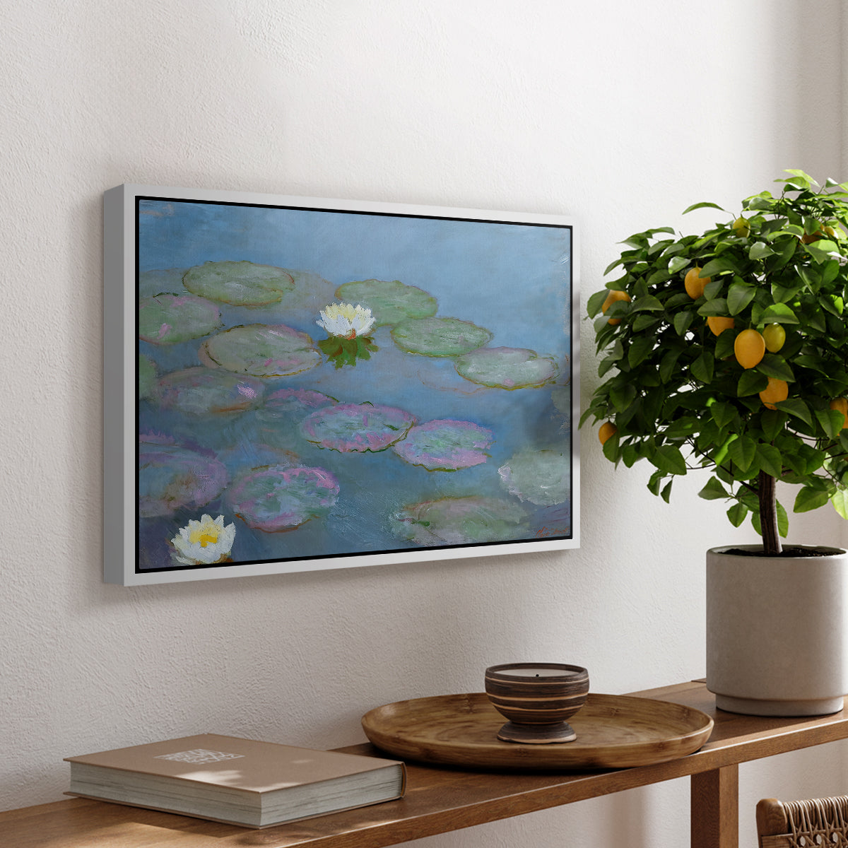 Water Lilies (Nymphéas), 1897-1899 by Claude Monet, presented in a white floater framed canvas featuring floating water lilies on pond with reflections of sky and foliage, displayed above a hallway console table.