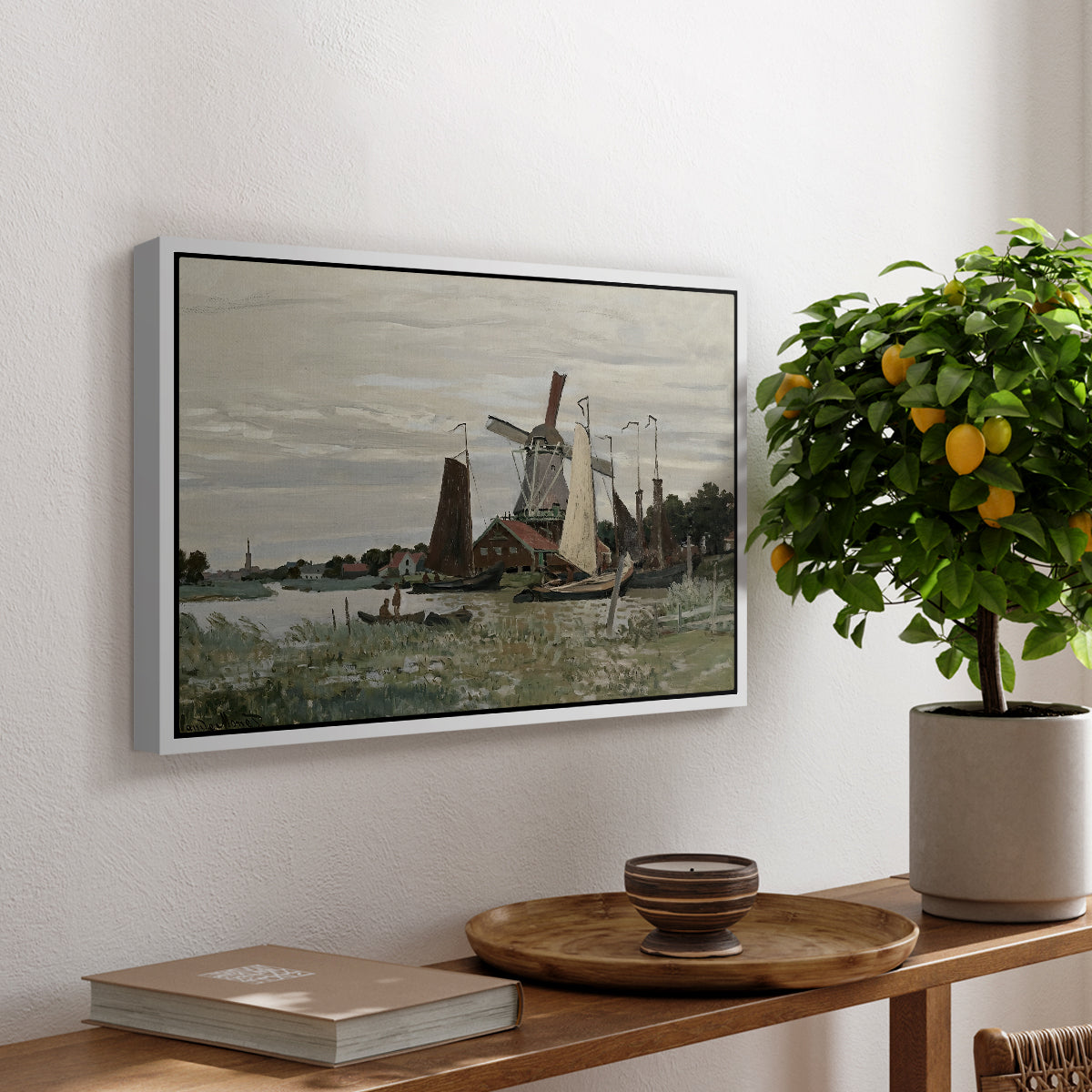 Windmill at Zaandam, 1871 by Claude Monet, presented in a white floater framed canvas featuring a single windmill beside water with surrounding buildings and sky, displayed above a hallway console table.