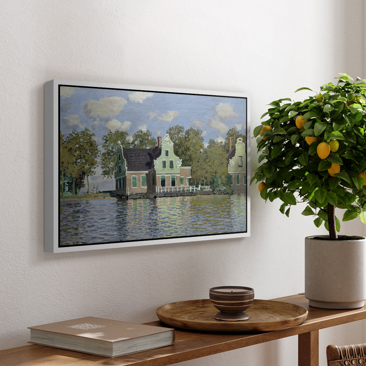 Houses on the Zaan River at Zaandam, 1871 by Claude Monet, presented in a white floater framed canvas featuring a row of houses along river with reflections in calm water, displayed above a hallway console table.