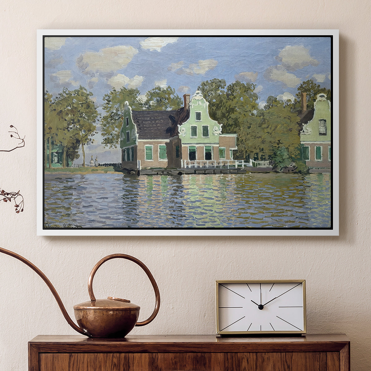 White floater framed canvas featuring a peaceful canal scene with houses mirrored in water, displayed above a cabinet in a soft-toned living room.