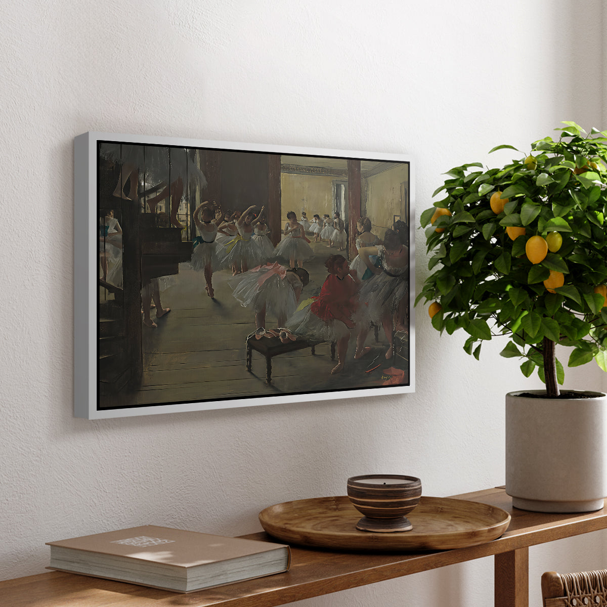 The Dance Class, c. 1873 by Edgar Degas, presented in a white floater framed canvas featuring ballerinas practicing in studio with instructor observing nearby, displayed above a hallway console table.