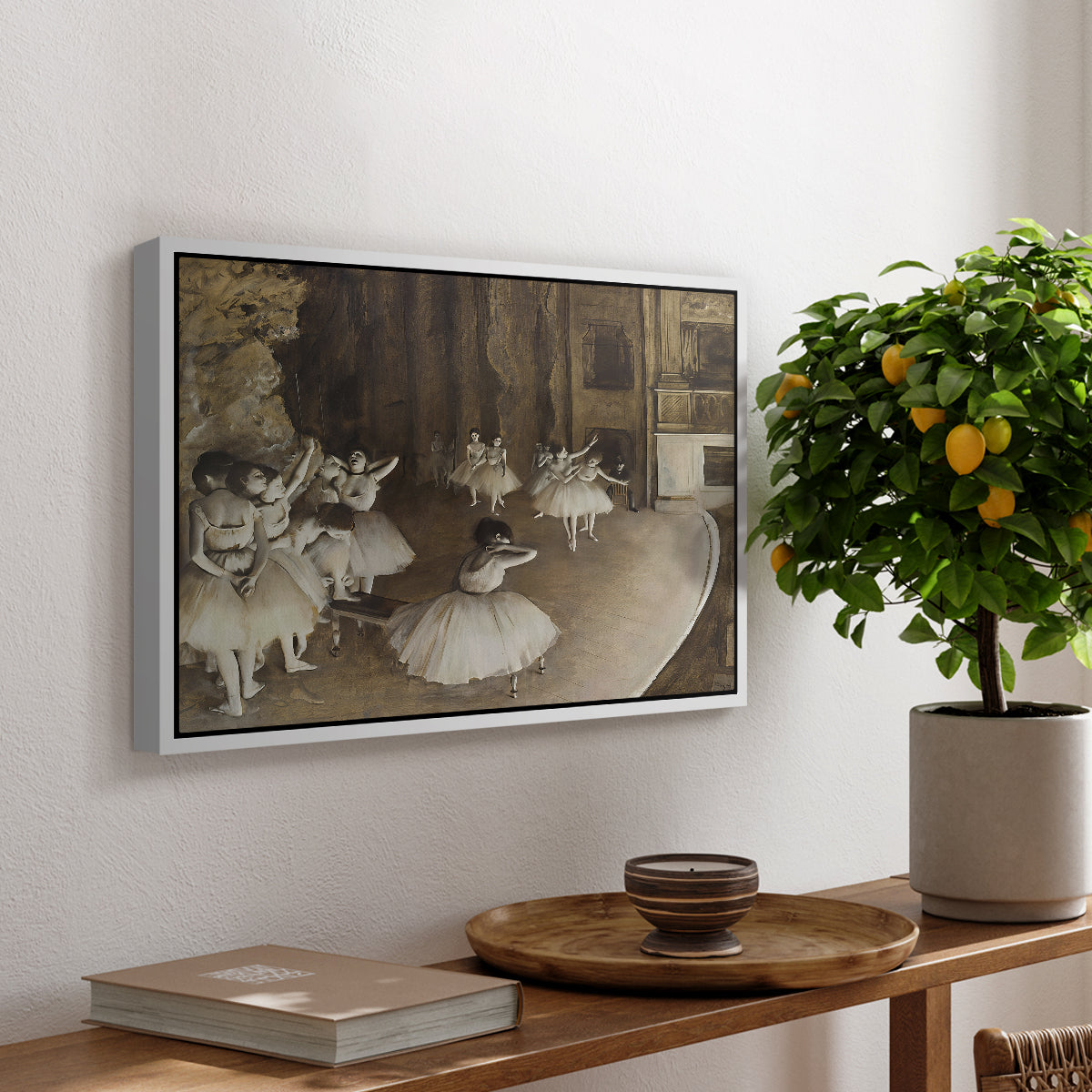The Rehearsal of the Ballet Onstage, 1874 by Edgar Degas, presented in a white floater framed canvas featuring ballerinas rehearsing on stage with set backdrop and lighting, displayed above a hallway console table.