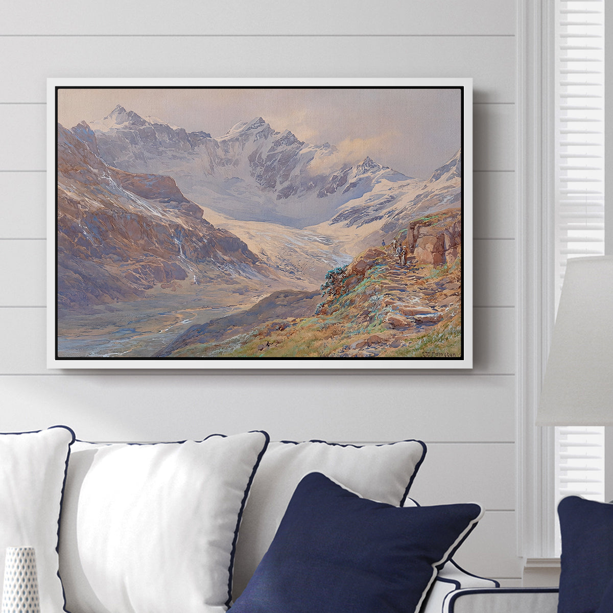 Odenwinklkees with the Johannisberg, 1902 by Edward Theodore Compton displayed above a sofa in a living room in a white floater frame, featuring a mountain scene with glacier stretching through rocky valley.