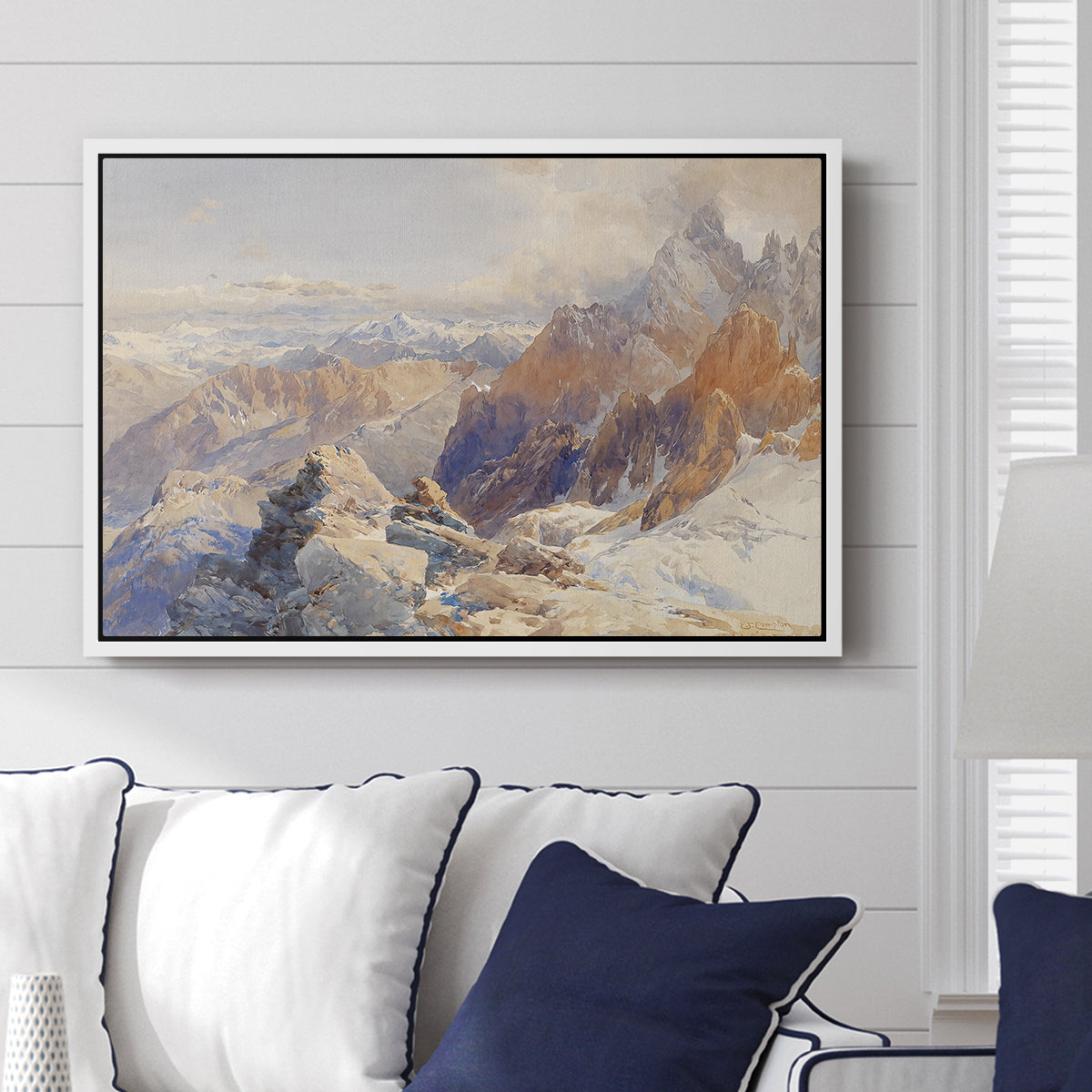 Col du Géant, 1903 by Edward Theodore Compton displayed above a sofa in a living room in a white floater frame, featuring a high mountain landscape featuring dramatic ridges and glacier terrain.