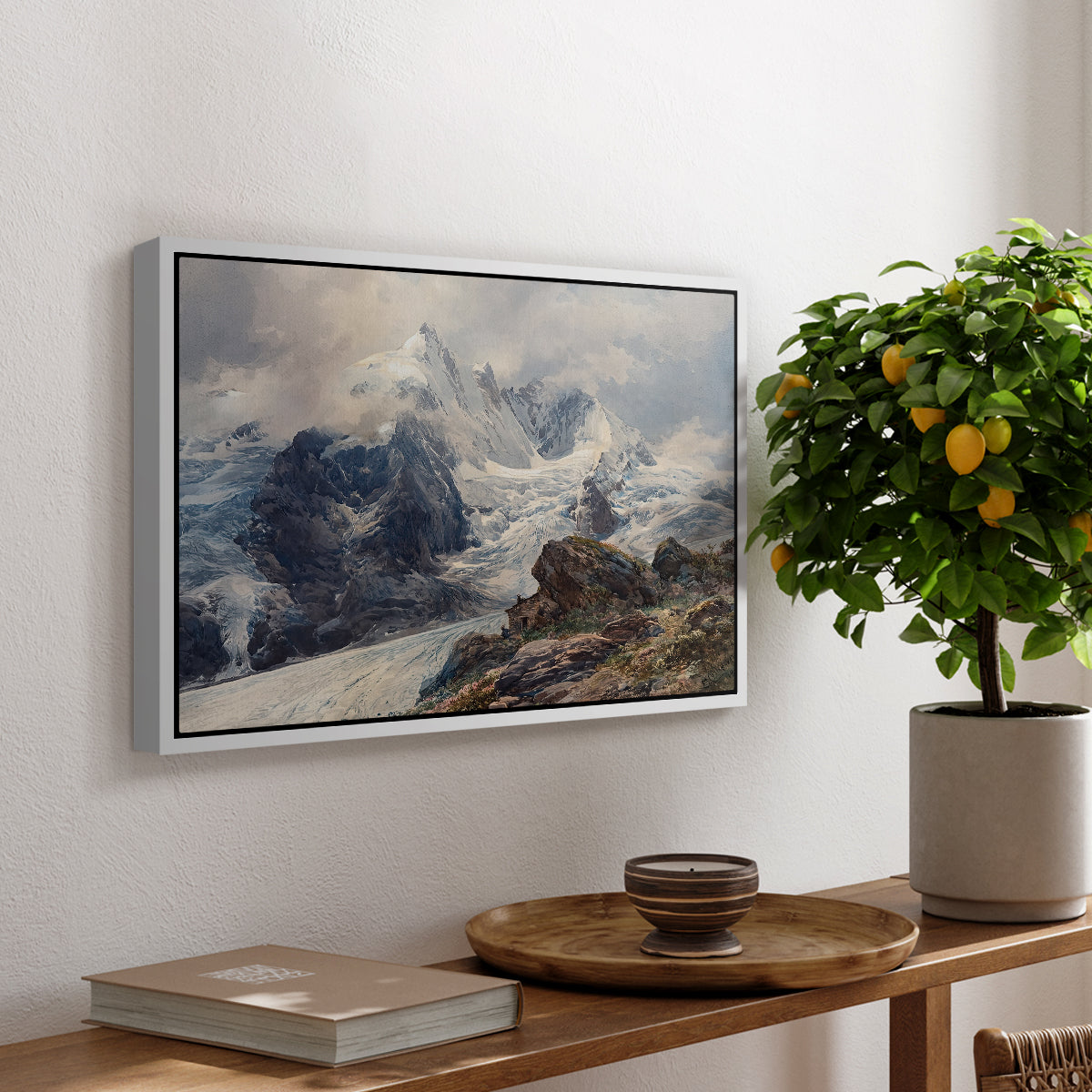 The Grossglockner, 1880 by Edward Theodore Compton, presented in a white floater framed canvas featuring a towering mountain peak rising above rocky alpine landscape, displayed above a hallway console table.