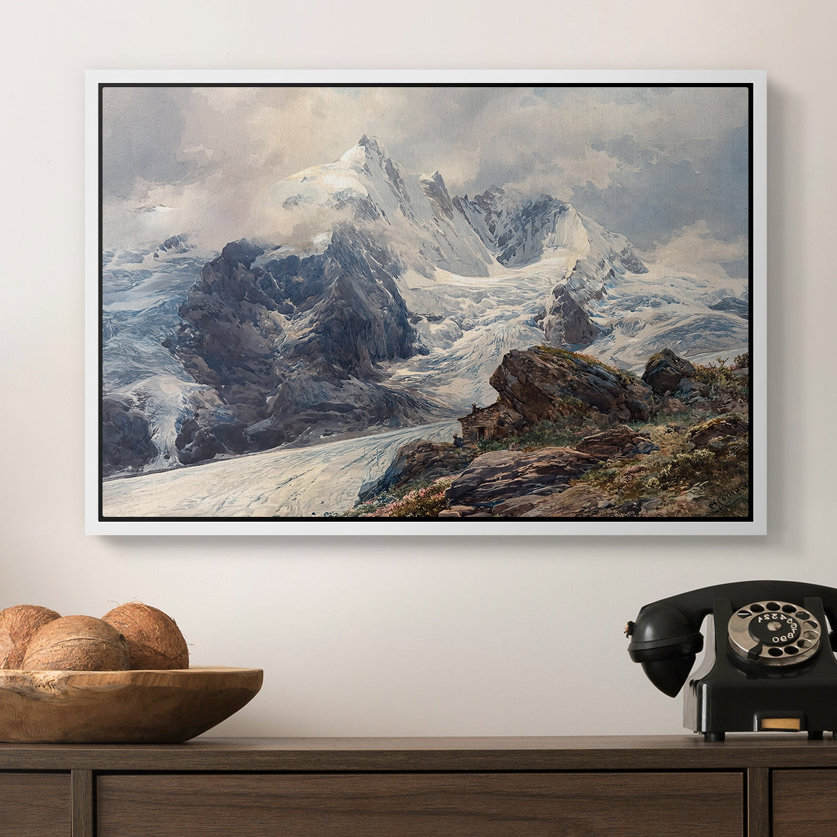 The Grossglockner, 1880 by Edward Theodore Compton in a white floater framed canvas displayed above a console table in a hallway, featuring an alpine peak dominating surrounding terrain.