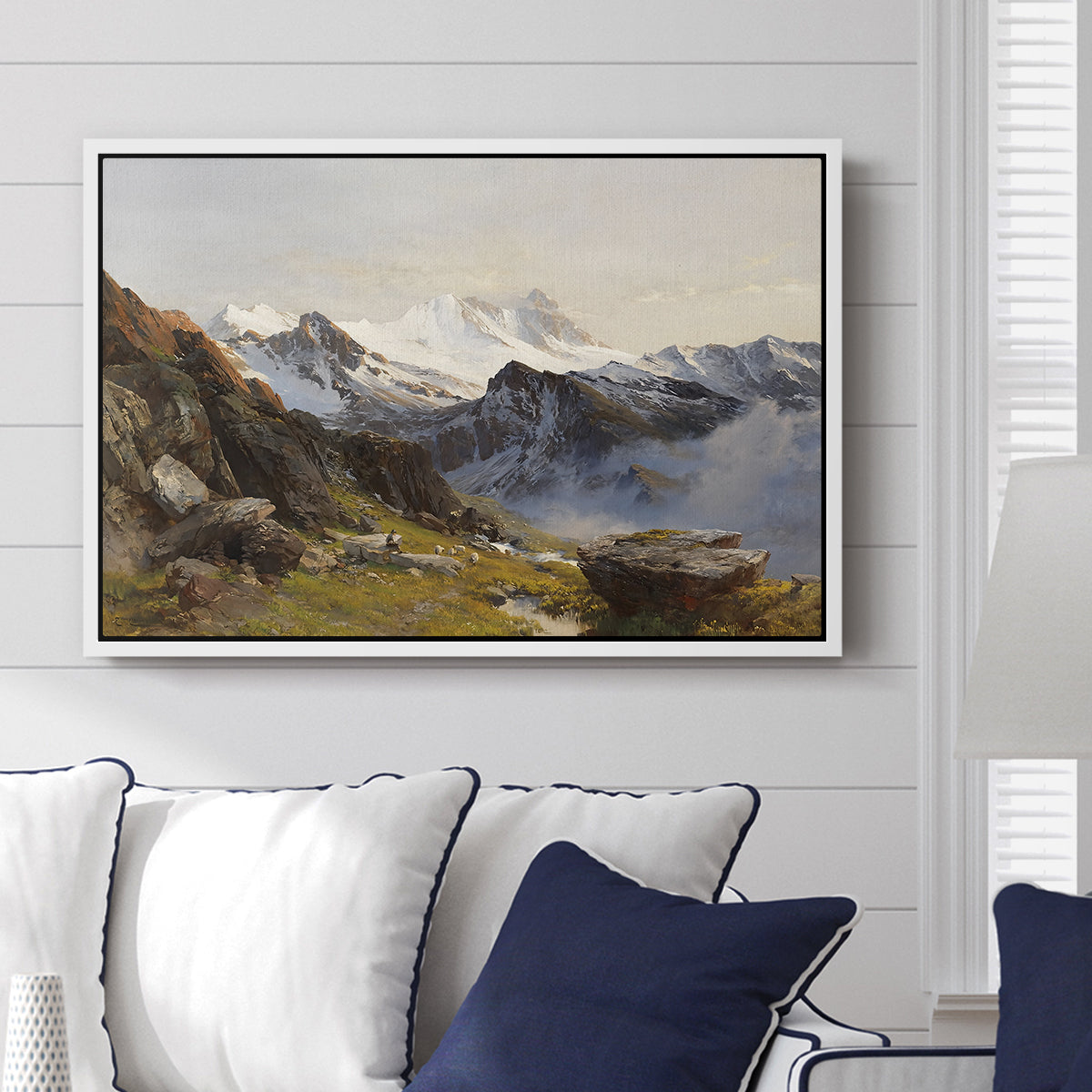 The Großglockner from the Prager Hut, 1890 by Edward Theodore Compton displayed above a sofa in a living room in a white floater frame, featuring a mountain summit seen from elevated viewpoint with surrounding landscape.