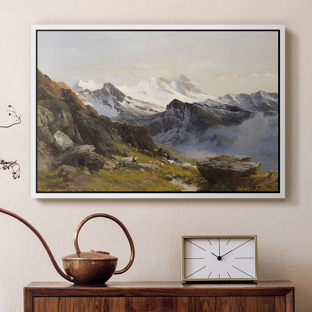 White floater framed canvas featuring an alpine vista with towering peak and foreground terrain, displayed above a cabinet in a soft-toned living room.