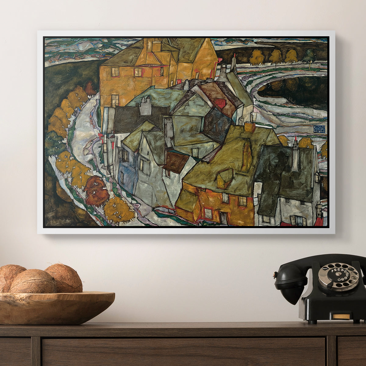 Crescent of Houses II (Island Town), 1915 by Egon Schiele in a white floater framed canvas displayed above a console table in a hallway, featuring an architectural scene with houses arranged in curved composition.