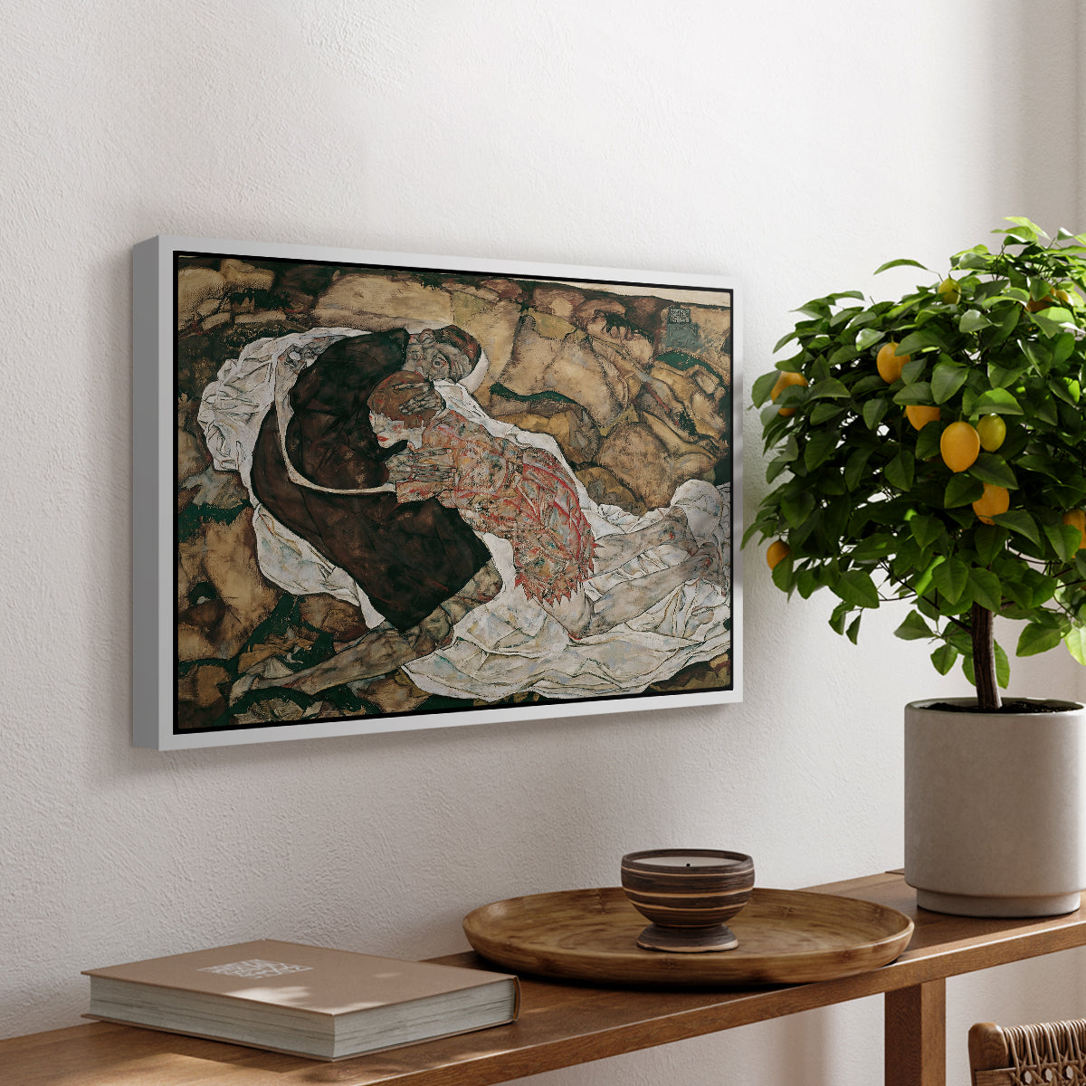 Death and the Maiden, 1915 by Egon Schiele, presented in a white floater framed canvas featuring intertwined figures representing death and woman in emotional embrace, displayed above a hallway console table.