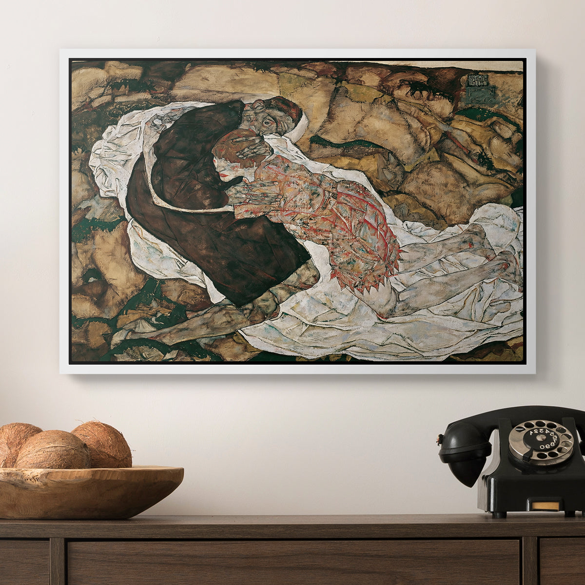 Death and the Maiden, 1915 by Egon Schiele in a white floater framed canvas displayed above a console table in a hallway, featuring an intense composition exploring life and death through figures.