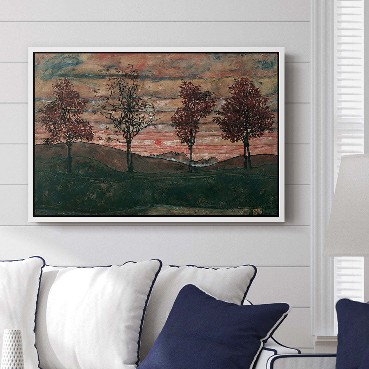 Four Trees, 1917 by Egon Schiele displayed above a sofa in a living room in a white floater frame, featuring a minimal landscape with grouped trees and expressive color.