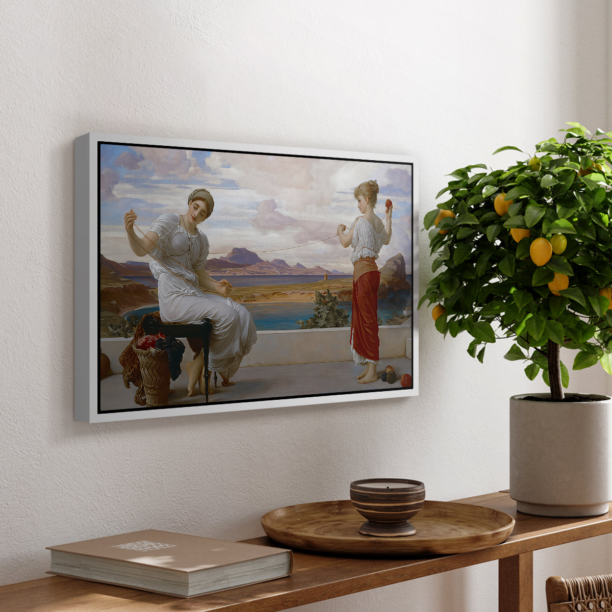 Winding the Skein, c. 1878 by Frederic Leighton, presented in a white floater framed canvas featuring a woman holding thread while another figure helps wind yarn in classical setting, displayed above a hallway console table.