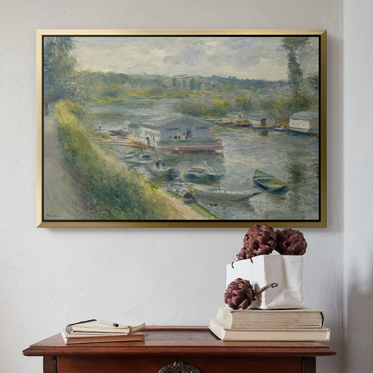 Gold floater framed canvas featuring Wash-House Boat at Bas-Meudon, c. 1874 by Pierre-Auguste Renoir above an entryway table in a minimalist foyer.