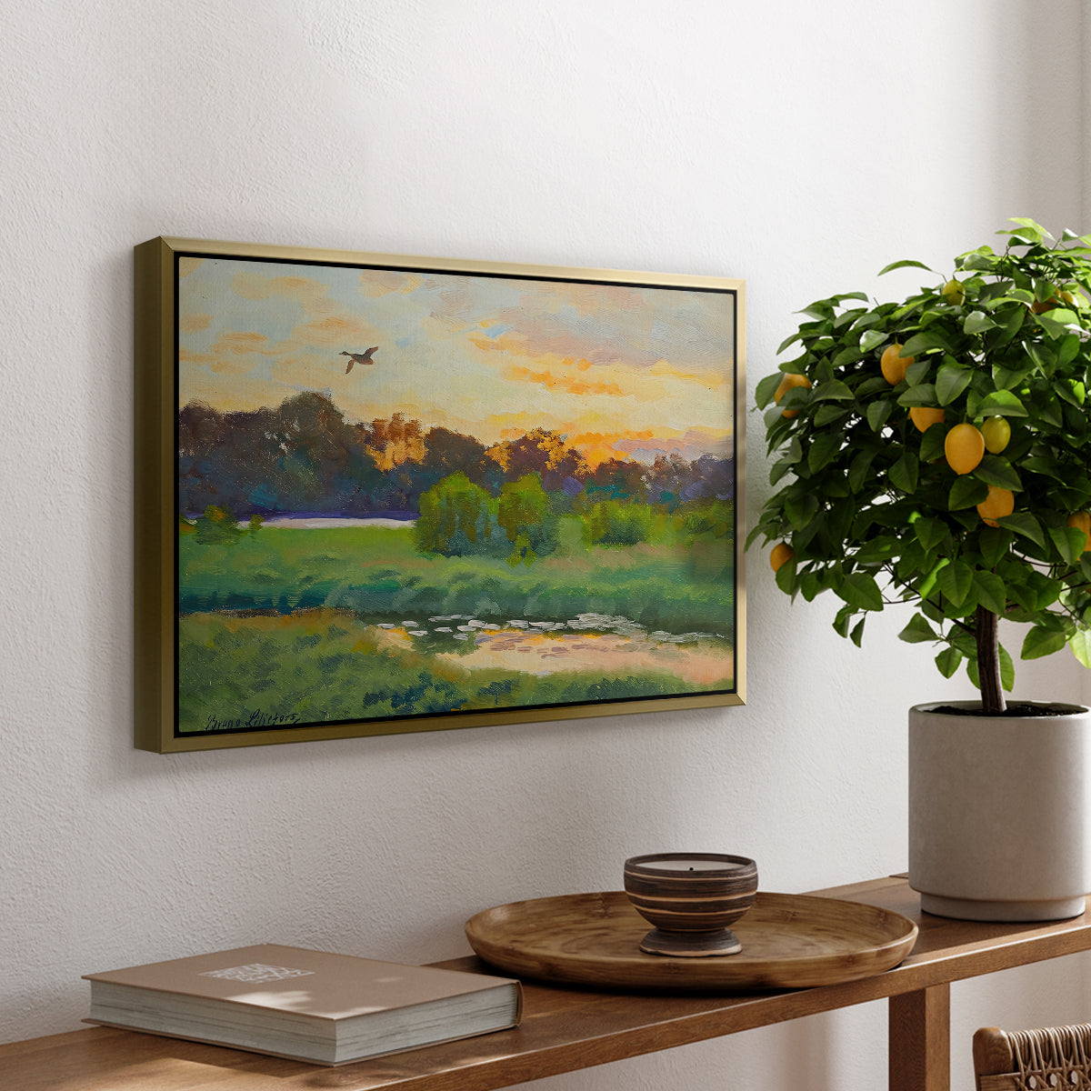 Flying Duck at Sunset, 1924 by Bruno Liljefors, presented in a gold floater framed canvas featuring a wild duck flying over a sunset marsh with trees, displayed above a hallway console table.