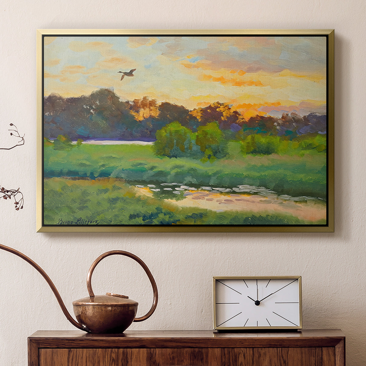 Gold floater framed canvas featuring a wild duck gliding through a golden sunset sky, displayed above a cabinet in a soft-toned living room.
