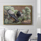 Hooded Crows (Kråkor), 1891 by Bruno Liljefors displayed above a sofa in a living room in a gold floater frame, featuring birds standing alert in natural field environment.
