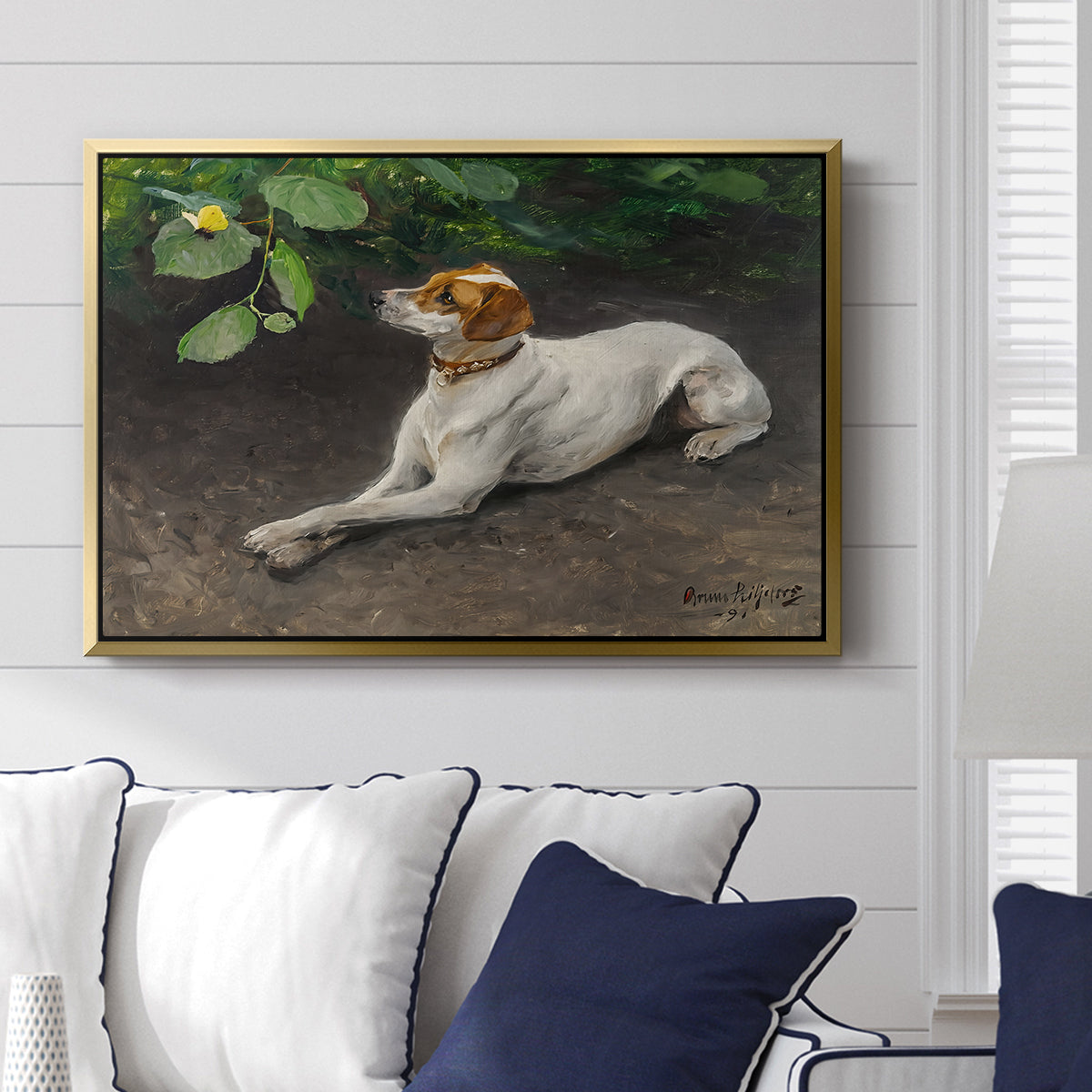 Portrait of a Dog, 1891 by Bruno Liljefors displayed above a sofa in a living room in a gold floater frame, featuring a realistic portrait of a resting dog with attentive expression.