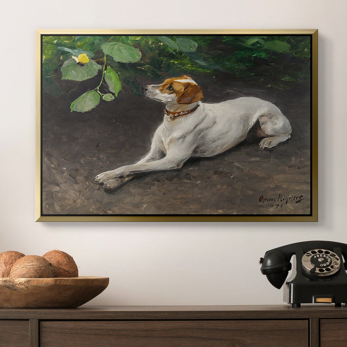 Portrait of a Dog, 1891 by Bruno Liljefors in a gold floater framed canvas displayed above a console table in a hallway, featuring a calm scene of dog reclining in open landscape.