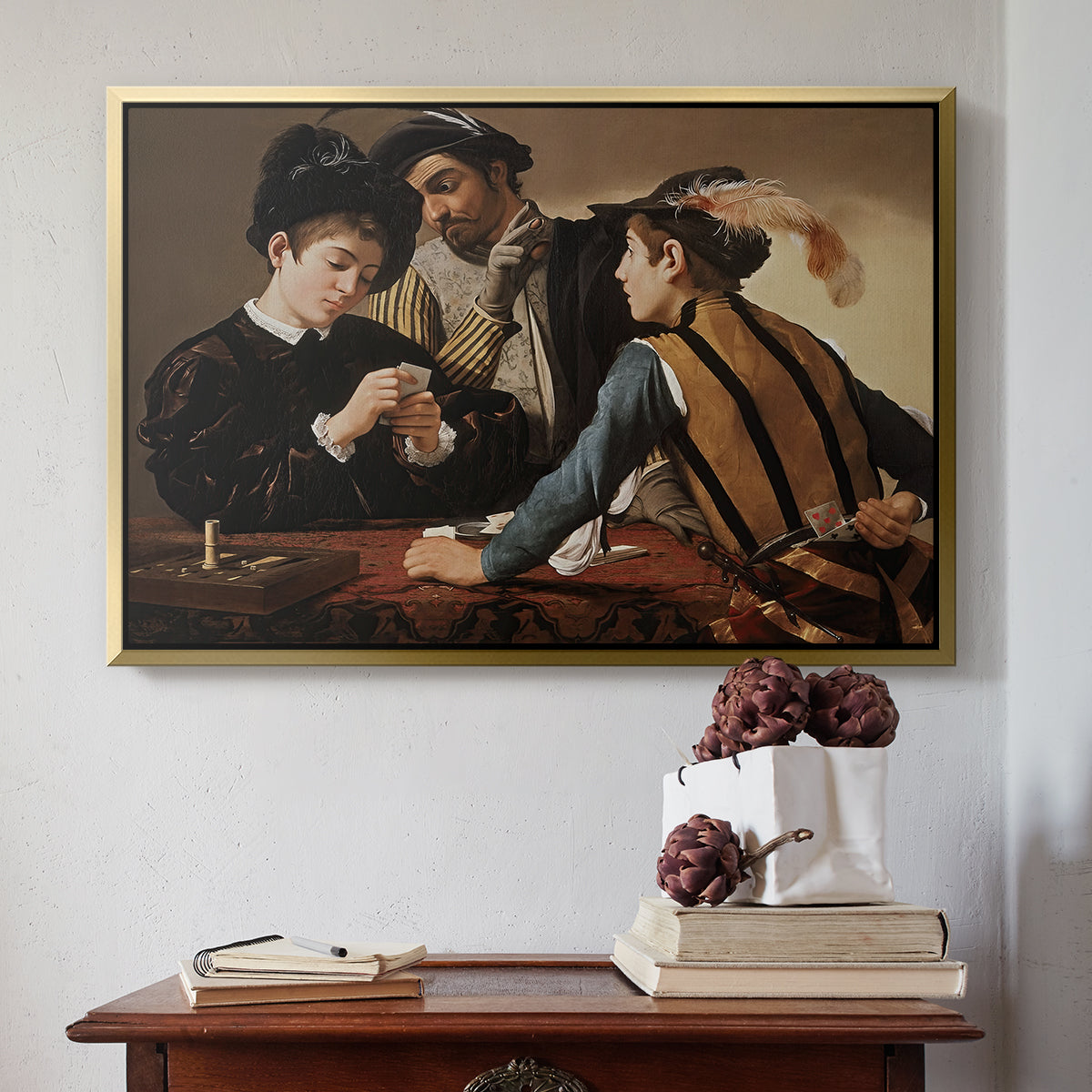 Gold floater framed canvas featuring The Cardsharps, c. 1594 by Caravaggio above an entryway table in a minimalist foyer.