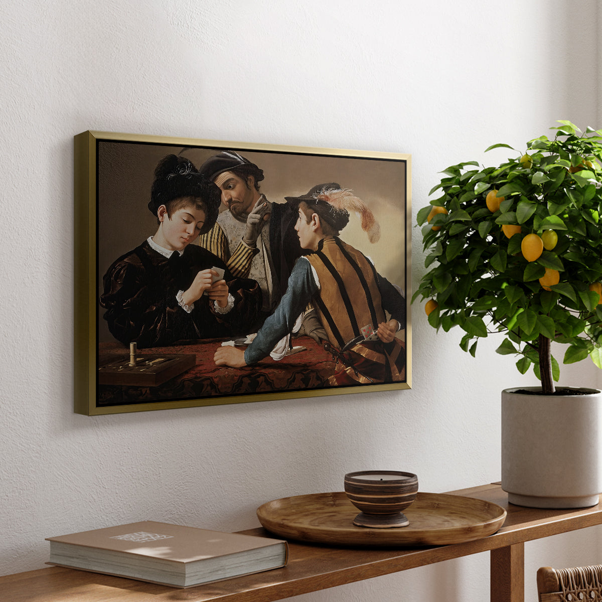 The Cardsharps, c. 1594 by Caravaggio, presented in a gold floater framed canvas featuring two men cheating at cards while a third figure secretly observes behind them, displayed above a hallway console table.