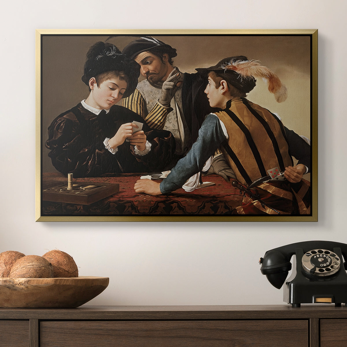 The Cardsharps, c. 1594 by Caravaggio in a gold floater framed canvas displayed above a console table in a hallway, featuring a dramatic interior scene of gambling and trickery among figures.