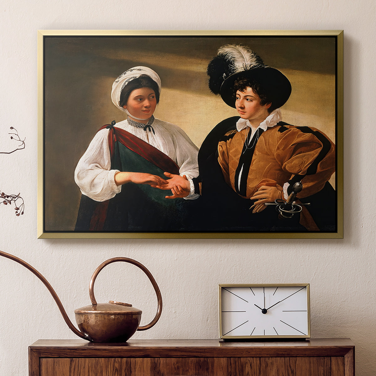 Gold floater framed canvas featuring an intimate scene of palm reading with subtle act of theft, displayed above a cabinet in a soft-toned living room.