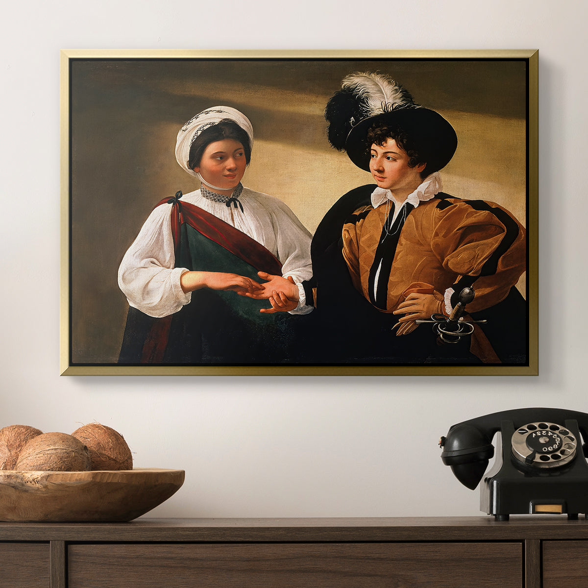 The Fortune Teller (Louvre Version), c. 1595 by Caravaggio in a gold floater framed canvas displayed above a console table in a hallway, featuring two figures engaged in fortune telling with hidden deception.
