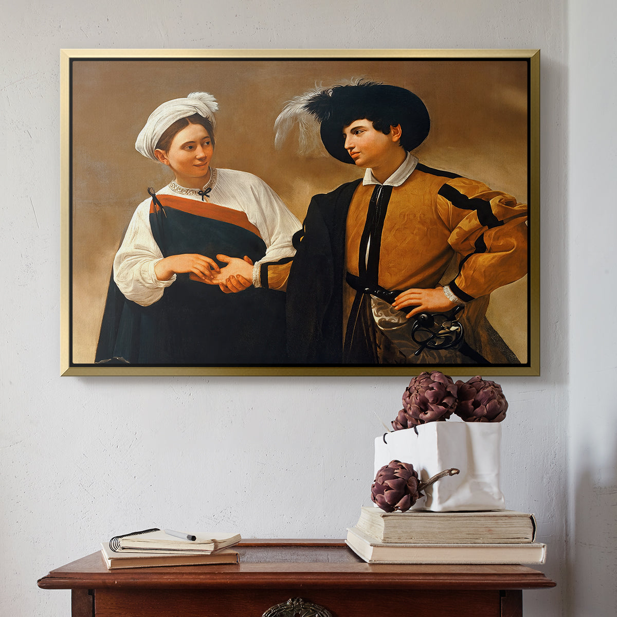 Gold floater framed canvas featuring The Fortune Teller (Capitoline Version), c. 1599 by Caravaggio above an entryway table in a minimalist foyer.