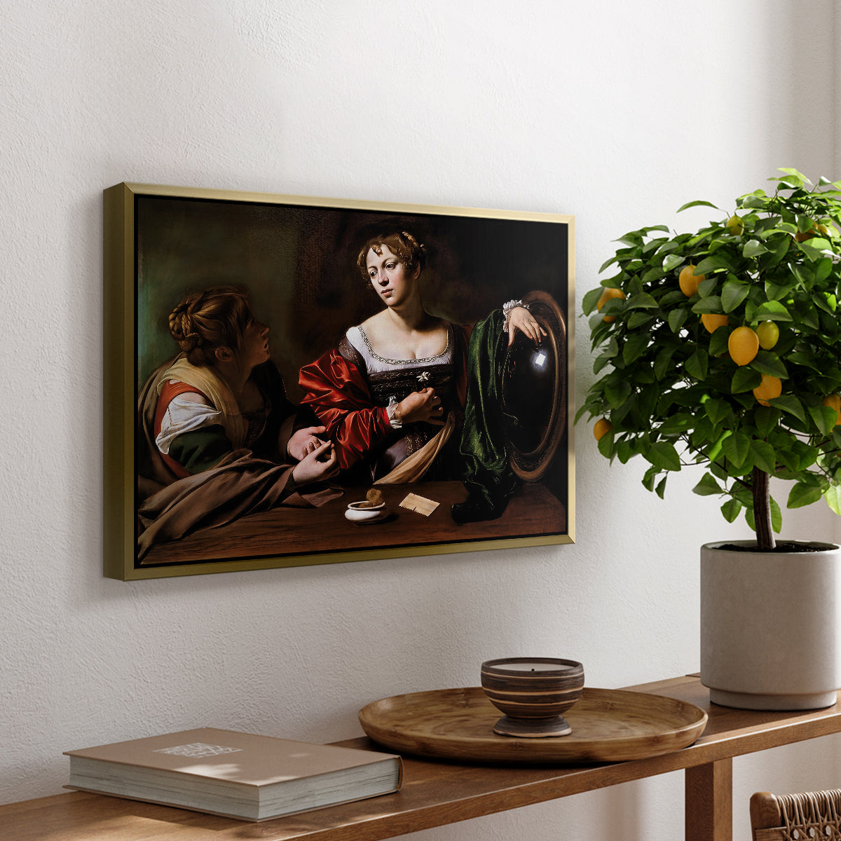 Martha and Mary Magdalene, c. 1598 by Caravaggio, presented in a gold floater framed canvas featuring a two women seated together in conversation with symbolic objects on table, displayed above a hallway console table.