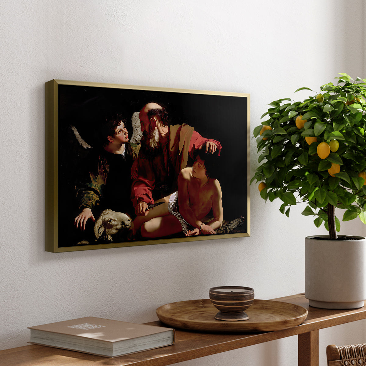 The Sacrifice of Isaac (Uffizi Version), c. 1603 by Caravaggio, presented in a gold floater framed canvas featuring Abraham holding Isaac while angel intervenes to stop the sacrifice, displayed above a hallway console table.