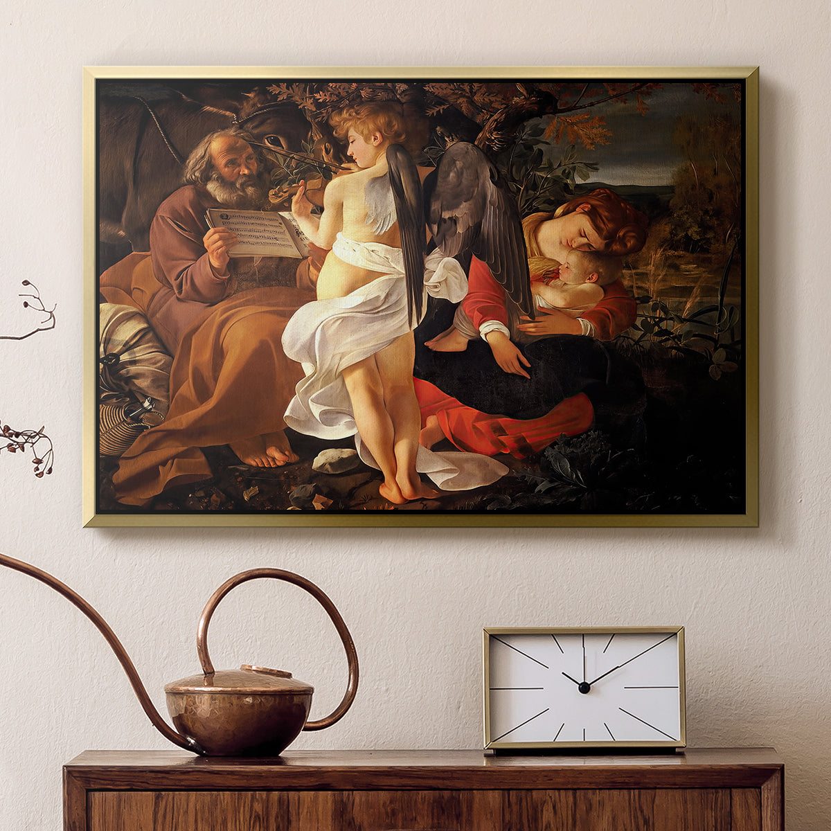 Gold floater framed canvas featuring a peaceful religious moment with figures reclining in natural setting, displayed above a cabinet in a soft-toned living room.