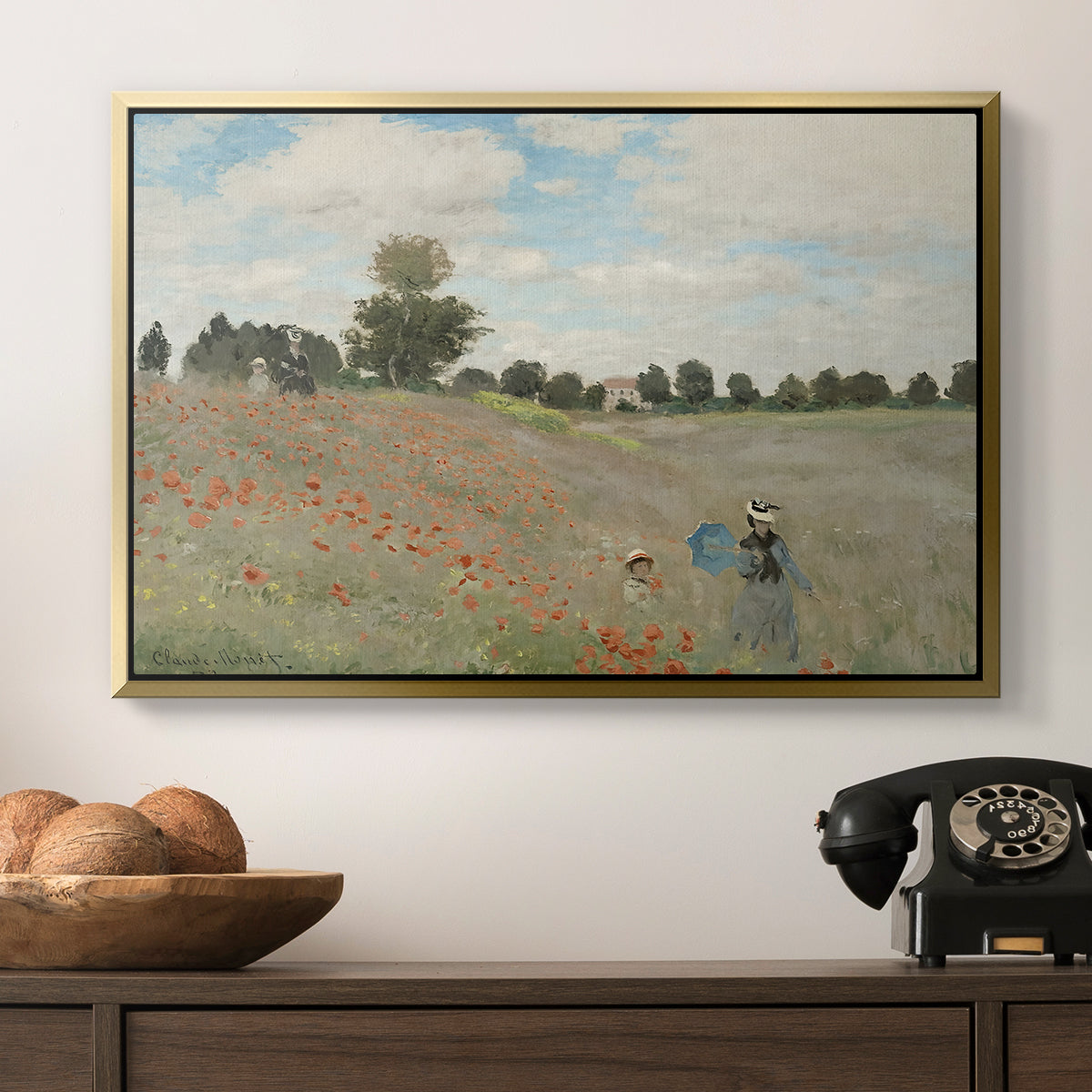 The Poppy Field near Argenteuil, 1873 by Claude Monet in a gold floater framed canvas displayed above a console table in a hallway, featuring a rural landscape with scattered figures among blooming flowers.