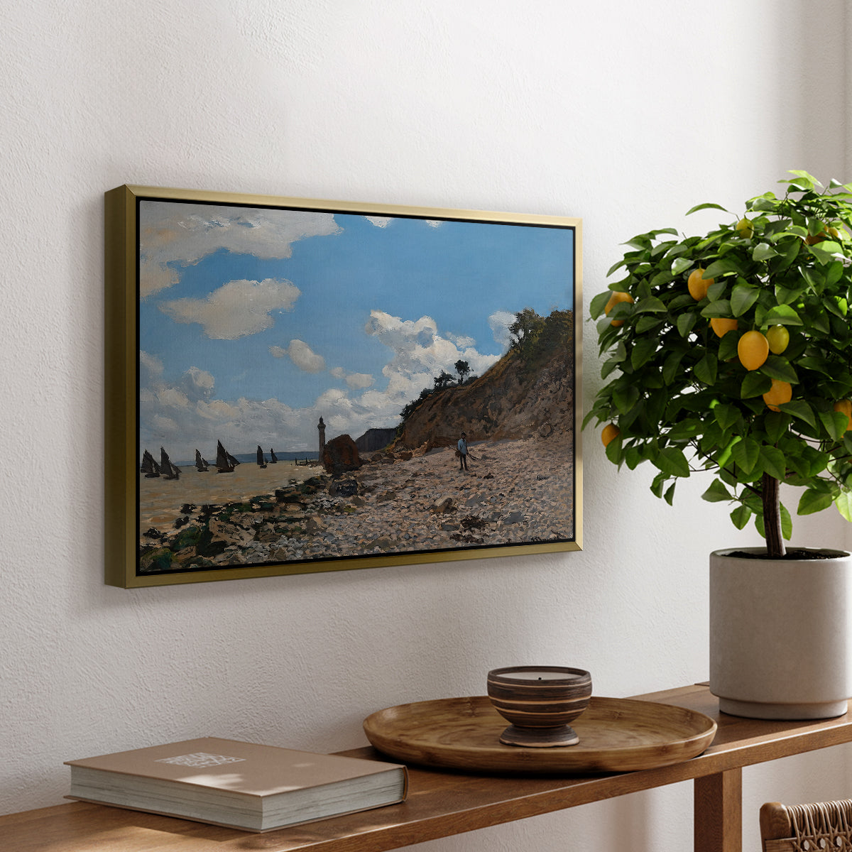 The Beach at Honfleur, 1864 by Claude Monet, presented in a gold floater framed canvas featuring a coastal beach scene with figures gathered along shoreline and boats nearby, displayed above a hallway console table.