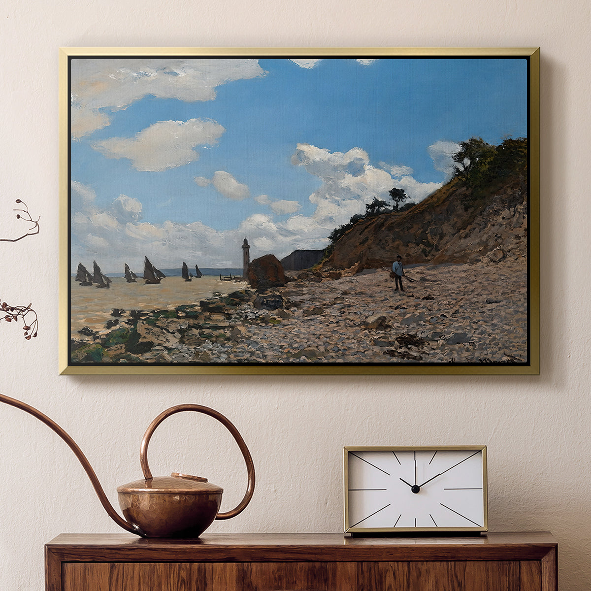 Gold floater framed canvas featuring a sandy beach with figures relaxing near water's edge, displayed above a cabinet in a soft-toned living room.