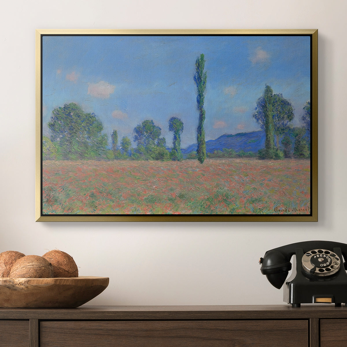 Poppy Field (Giverny), 1890-1891 by Claude Monet in a gold floater framed canvas displayed above a console table in a hallway, featuring a rural field filled with red blossoms beneath open sky.
