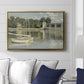The Bridge at Argenteuil, 1874 by Claude Monet displayed above a sofa in a living room in a gold floater frame, featuring an impressionist river scene with boats passing beneath bridge.