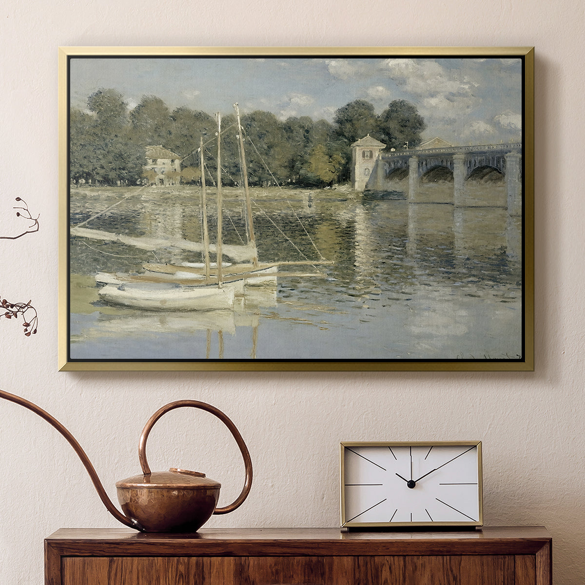Gold floater framed canvas featuring a bright landscape featuring bridge and sailboats on calm water, displayed above a cabinet in a soft-toned living room.