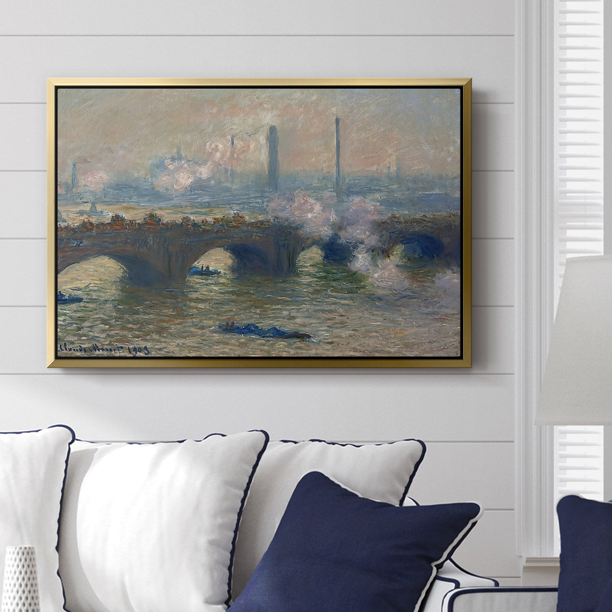 Waterloo Bridge, Gray Day, 1903 by Claude Monet displayed above a sofa in a living room in a gold floater frame, featuring an impressionist depiction of bridge with soft gray tones and haze.