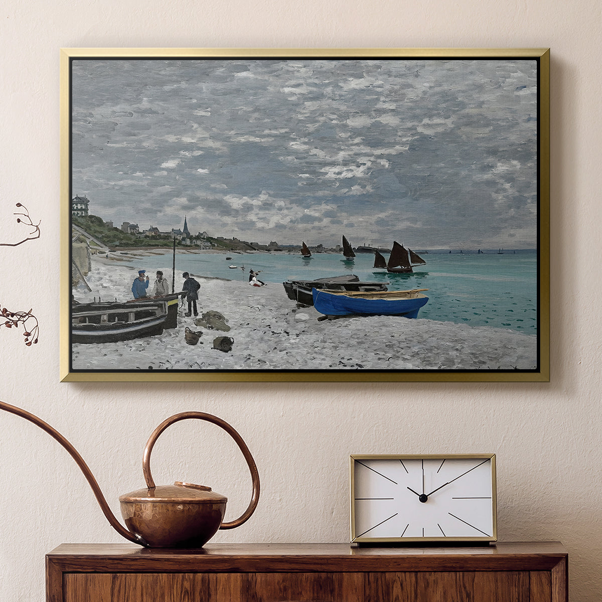 Gold floater framed canvas featuring a coastal landscape with sailboats and visitors on cliffside, displayed above a cabinet in a soft-toned living room.