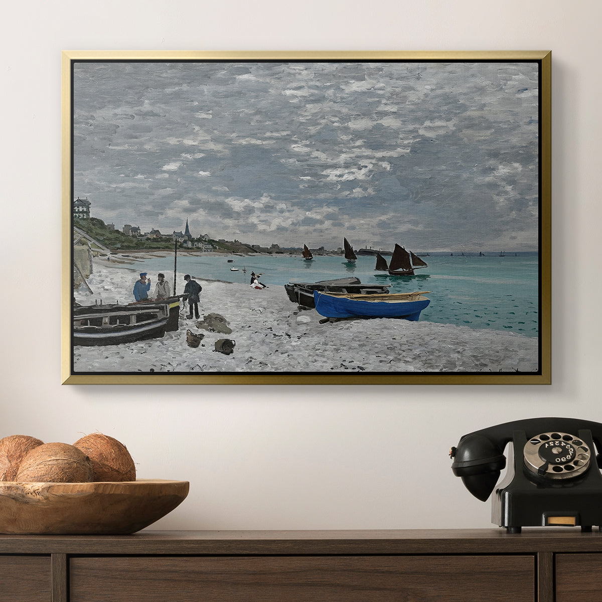 The Beach at Sainte-Adresse, 1867 by Claude Monet in a gold floater framed canvas displayed above a console table in a hallway, featuring an impressionist seaside gathering with flags and ocean view.
