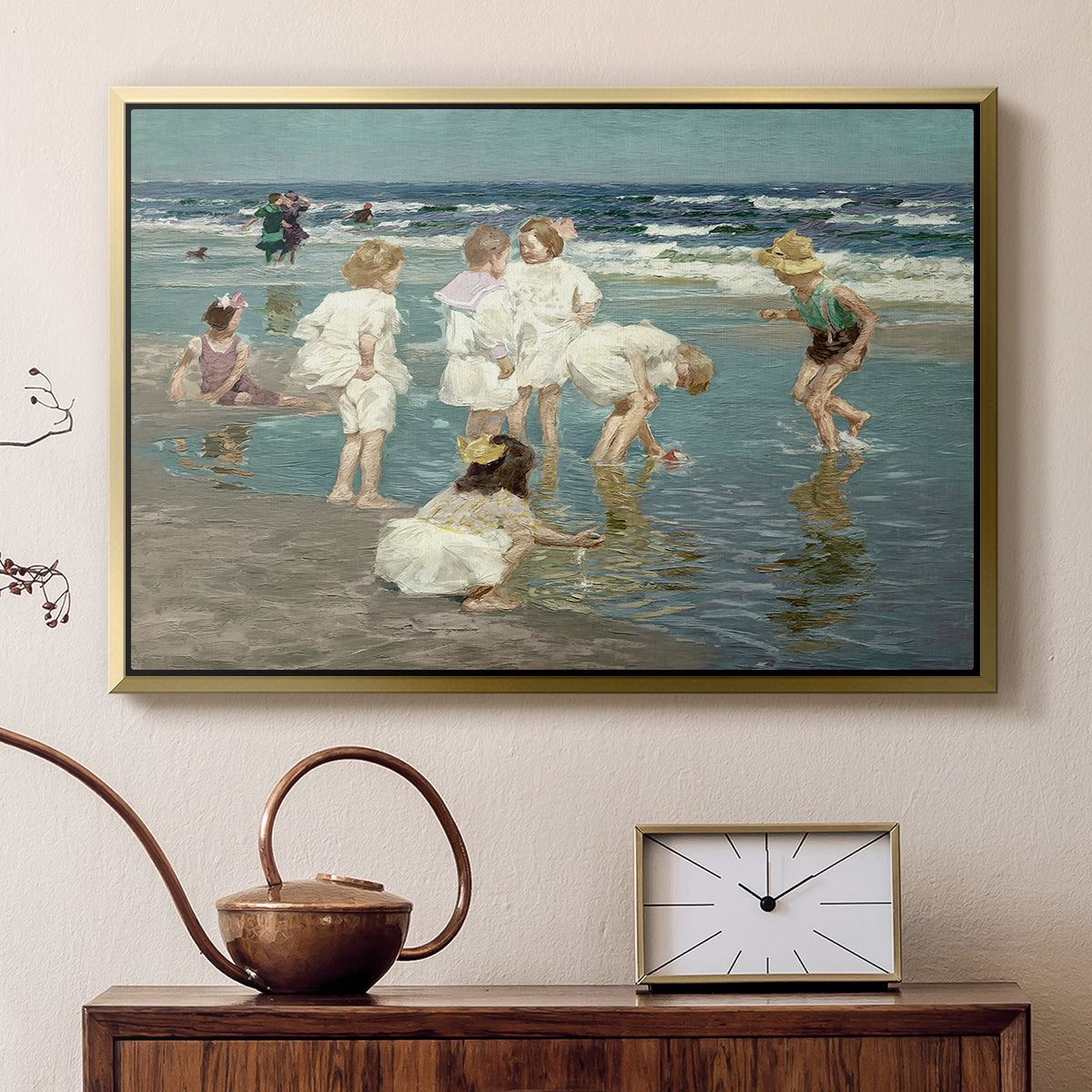 Gold floater framed canvas featuring an impressionist coastal view of families enjoying seaside water, displayed above a cabinet in a soft-toned living room.