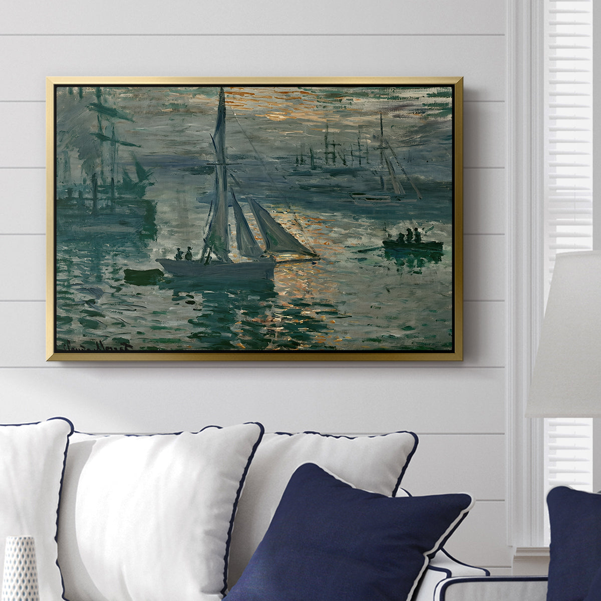 Sunrise (Marine), 1873 by Claude Monet displayed above a sofa in a living room in a gold floater frame, featuring an impressionist seascape with glowing sun and misty water.