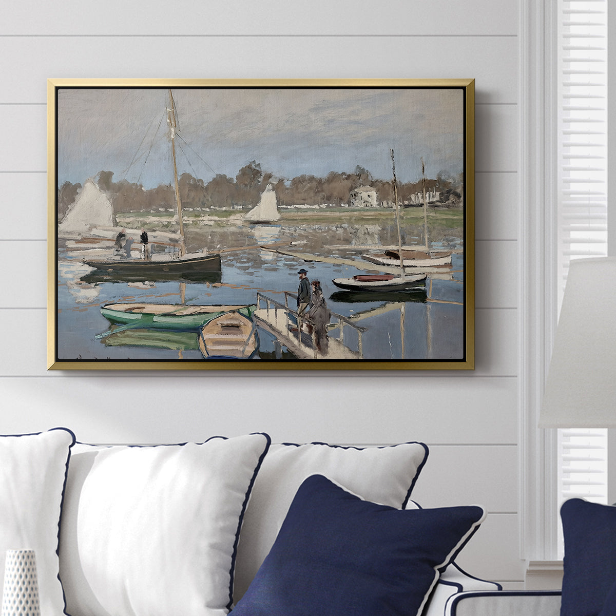 The Basin at Argenteuil, 1874 by Claude Monet displayed above a sofa in a living room in a gold floater frame, featuring an impressionist boating scene with clustered masts and gentle ripples.
