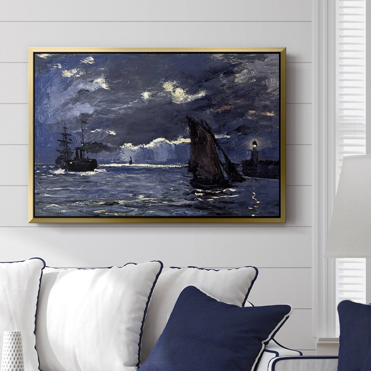 A Seascape, Shipping by Moonlight, 1864 by Claude Monet displayed above a sofa in a living room in a gold floater frame, featuring a nocturnal seascape with boats silhouetted against glowing moon.