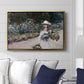 Young Girl in the Garden at Giverny, 1888 by Claude Monet displayed above a sofa in a living room in a gold floater frame, featuring an impressionist garden scene with child among greenery and blossoms.