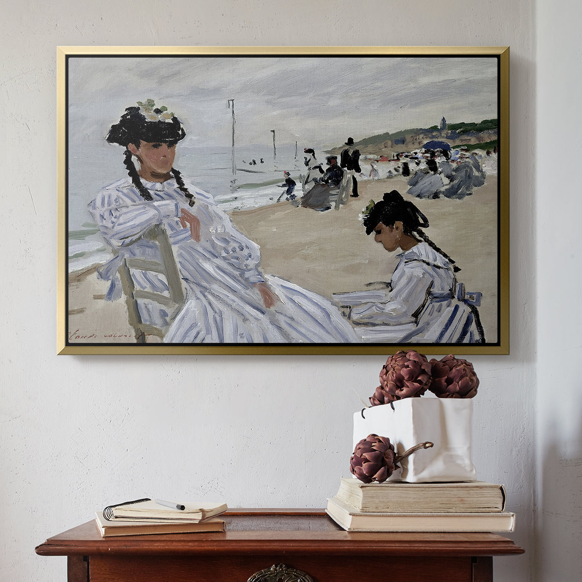 Gold floater framed canvas featuring On the Beach at Trouville, 1870 by Claude Monet above an entryway table in a minimalist foyer.