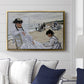 On the Beach at Trouville, 1870 by Claude Monet displayed above a sofa in a living room in a gold floater frame, featuring an impressionist seaside scene with women in dresses and hats.